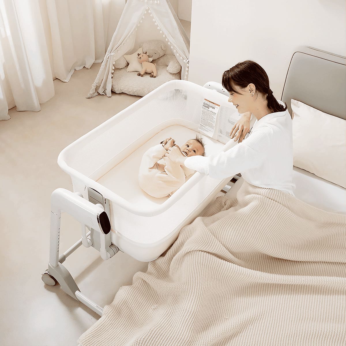 Maydolly 506 white smart electric cradle positioned beside a bed with parent and baby