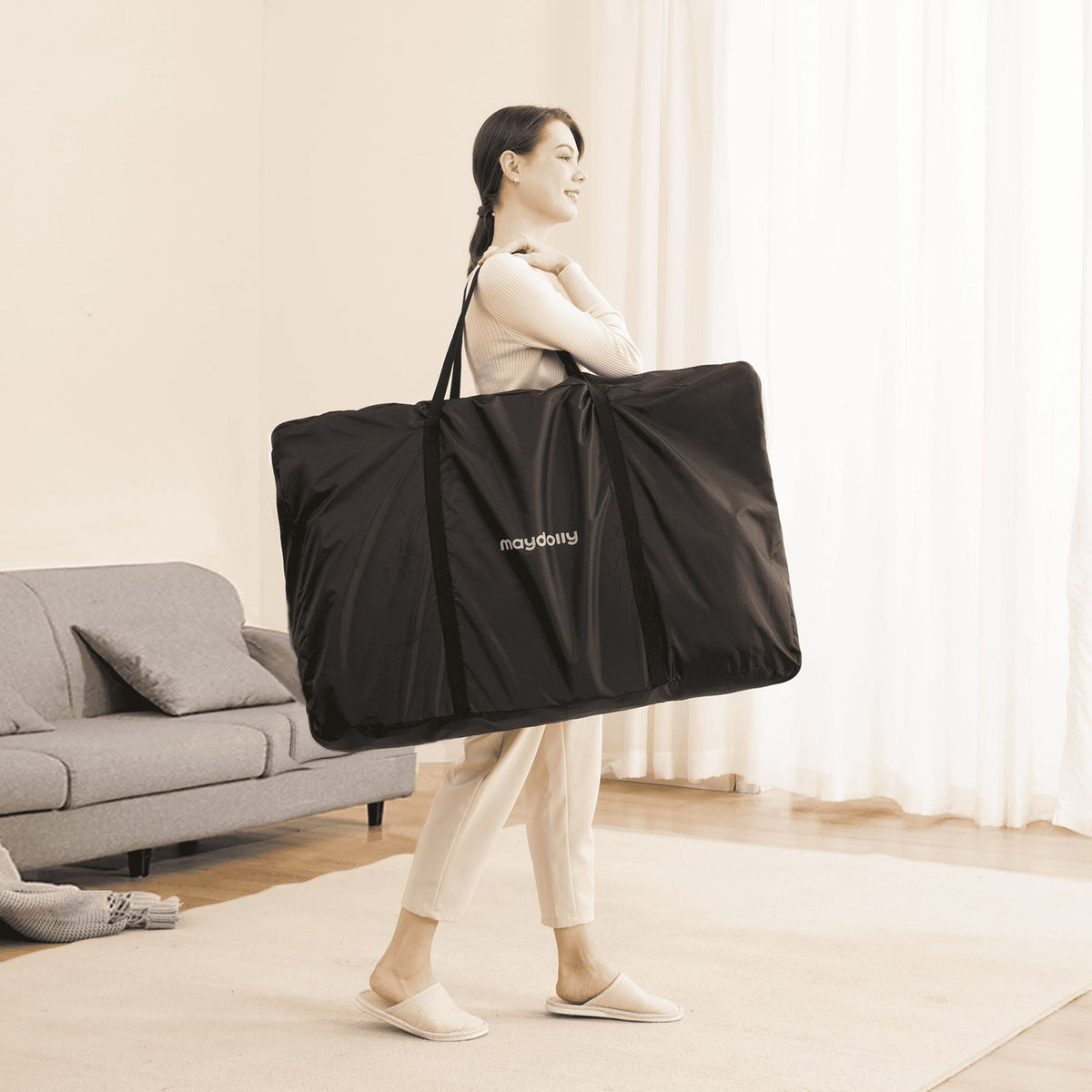 Parent carrying the folded Maydolly C03 Plus in its black travel bag